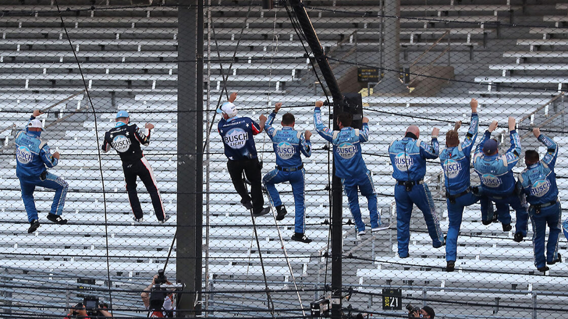 Kevin Harvick and his team climbing the fence after the Brickyard 400